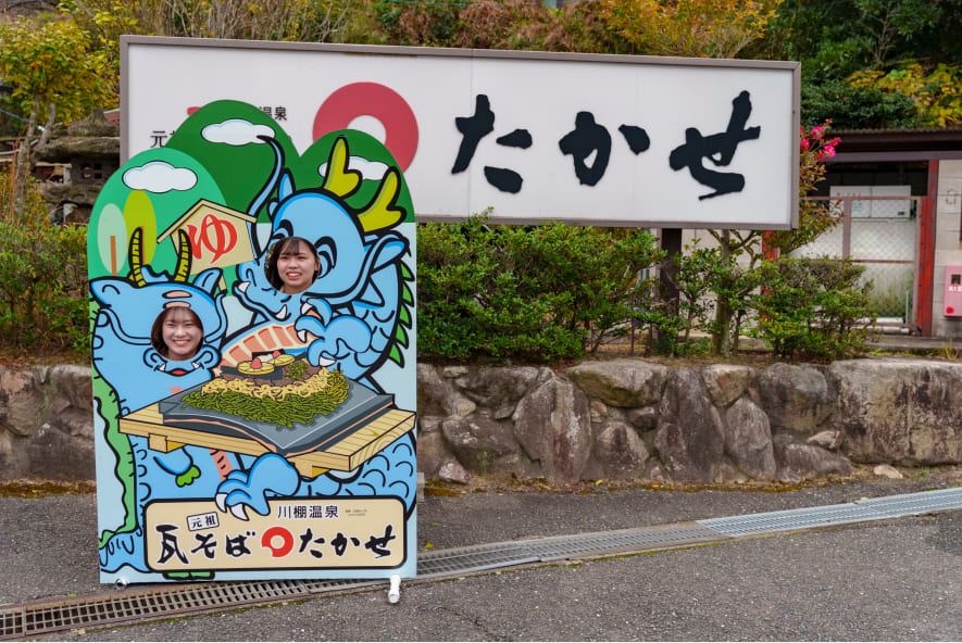「元祖瓦そばたかせ」の顔抜きパネルで写真を撮るスマイルサポーター